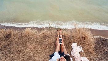 beautiful young girl sitting and holding a smartphone in her hands, top view photo