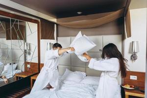 Cheerful couple have fun in the bedroom fighting with big pillows at home photo