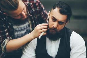 barber shaves a bearded man in vintage atmosphere photo