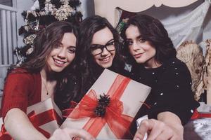 Beautiful girl shows Christmas gifts directly into the camera. Decorative vintage apartment. photo