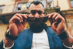 elegante hombre barbudo se quita las gafas foto