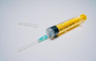 One one-off yellow medical syringe with needle lying photo