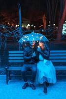 Guy and girl sitting on a bench under an umbrella photo