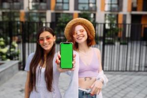 Girlfriends shows their phone to the camera photo
