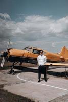 A man standing on the background of a small single engine plane. photo