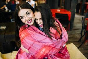 Two young and beautiful girls having fun in cafe photo