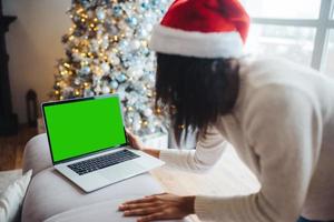 Female wearing santa hat while speaking with online friend on laptop photo