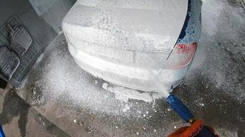 Young man covered soap suds on his car photo