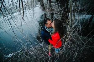 hermosa pareja posando cerca de un río congelado foto