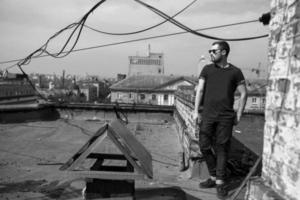 The man in the authentic boots and jeans selvedge on the roof of the building in the old town photo