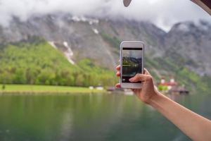 turista intenta tomar fotos con su teléfono inteligente en el lago hallstatter