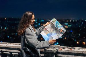 chica con un mapa en el fondo de la ciudad nocturna foto