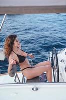 Fashion outdoor photo of beautiful young woman steering yacht