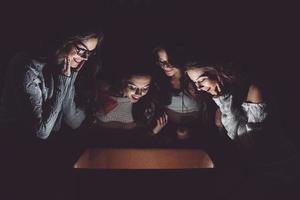 las hermanas abren una caja con un regalo de navidad y miran fascinadas dentro foto