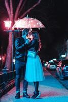 Guy and girl kissing under an umbrella photo