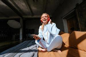 Natural smiling blonde listening to music in bedroom photo