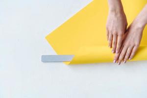 Women's hands wrap a gray nail file in paper photo