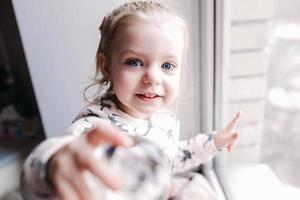 Little girl sitting near the window photo