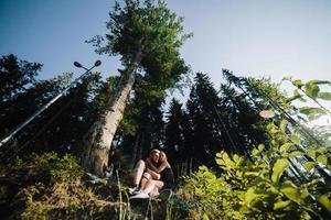 beautiful couple sitting in a forest near the tree photo