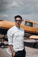 A man standing on the background of a small single engine plane. photo