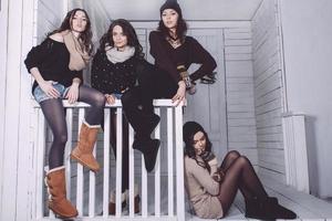 Four stylish models posing sitting on the fence. Christmas background photo