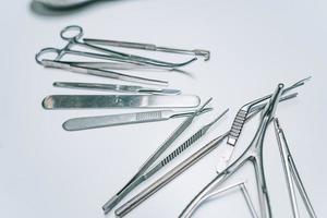 Several surgical instruments lie on a white table photo