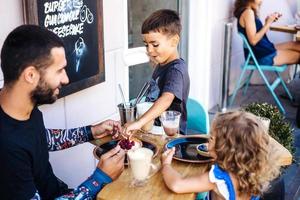 Dad, daughter and son are eating dessert photo