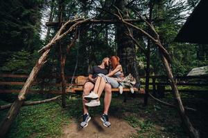 beautiful couple together with dog on a swing photo