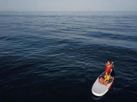 Mother with two daughters stand up on a paddle board photo