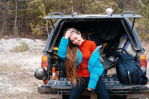 Young woman enjoying nature while sitting in the car trunk photo