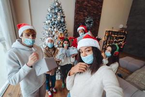 Multiethnic group of friends in Santa hats with gifts in hands. photo