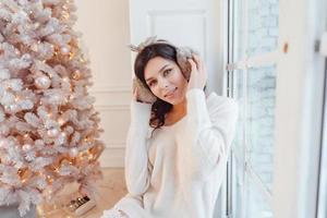 Young woman in an elegant dress near the Christmas tree photo