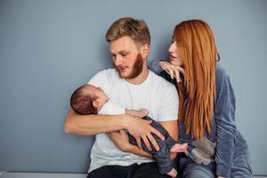 Young family with a baby by the wall photo