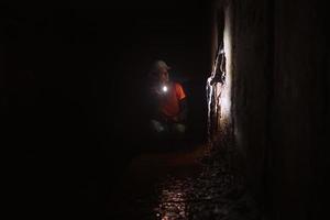 Female digger with flashlight explores the tunnel photo