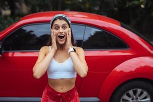 retrato de una mujer bastante caucásica parada contra un auto rojo nuevo foto