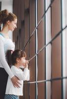 Two girls of different ages stare in a window in the gym photo