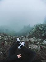 hombre en el acantilado mira la niebla foto