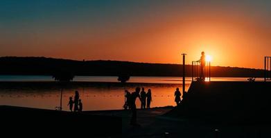 people are resting on a sports field by the river bank photo