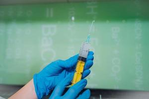 Hands in rubber gloves hold a disposable medical syringe with the drug photo