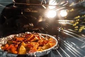 Baked potatoes with carrot and other spices in roasting pan. photo