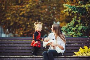 mother and two daughters rest on a bench photo