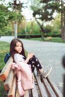 niña con un teléfono inteligente sentado en un banco foto