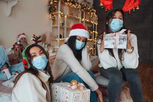 Multiethnic group of friends in Santa hats with gifts in hands. photo