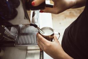 el barista está haciendo leche hervida. él usa una máquina de café especial para ello. foto