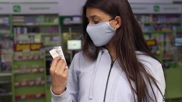 frau, die eine maske trägt, hält und zeigt medikamente in der apotheke video