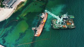 Rescue ship with crane lifting wrecked cargo ship at port in Odessa video