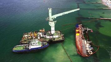 barco de rescate con grúa levantando un barco de carga naufragado en el puerto de odessa video