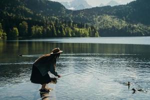 una joven hermosa alimenta a un pato junto al lago foto