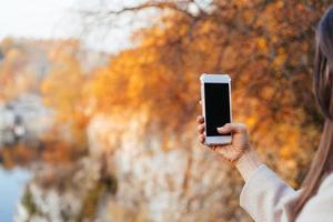 mano femenina sosteniendo un teléfono, pantalla negra foto