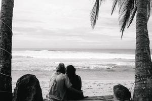 couple sitting under palm trees photo